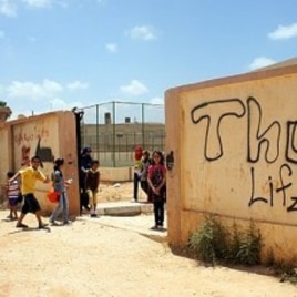 Children play outside their grafitti-covered school yard, closed for months after the uprising, Benghazi (File Photo - June 26, 2011)