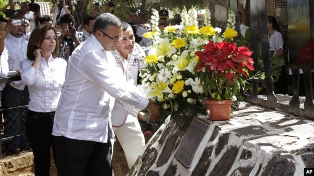 El presidente de El Salvador, Mauricio Funes y un residente de El Mozote, colocan una ofrenda floran en el monumento que honra las víctimas de la masacre que tuvo lugar en 1981.