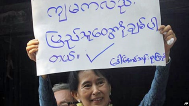 Myanmar's pro-democracy leader Aung San Suu Kyi displays a placard that reads, "I also love the people," to her supporters at the headquarters of her National League for Democracy Party in Yangon, Burma, 14 November 2010