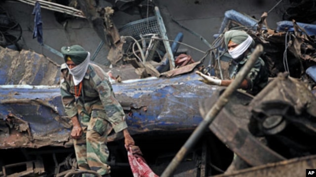 Indian army personnel pull out the body of a victim from the wreckage of a Kalka Mail passenger train that derailed near Fatehpur in Uttar Pradesh state, India, July 11, 2011