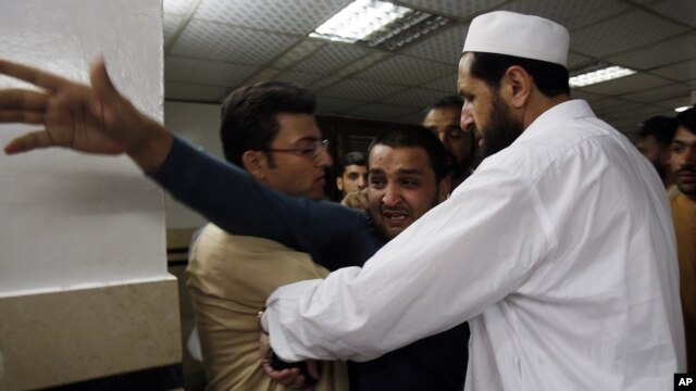 People comfort a man at a local hospital, who lost two cousins in an attack in Peshawar, Pakistan, April 29, 2013.