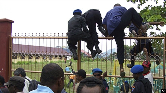 Papuanese who attended the Third Papuan People Congress climb a fence after police and troops dispersed the crowd at the event in Abepura in Indonesia's Papua province, October 19, 2011.