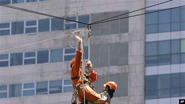 Rescuers carry people acting as victims as they rappel down a high-rise building during the National Earthquake Drill at the Ortigas commercial center as part of a disaster preparedness effort in suburban Pasig City, east of Manila, Philippines, June 2010