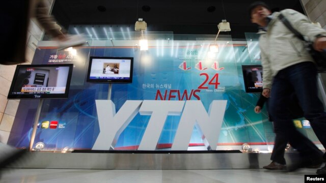 A TV crew walks by at the main office of television network YTN, in Seoul, March 20, 2013.