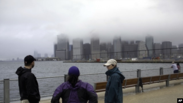 Three local residents stand at  the East River in the Brooklyn borough of New York City after hurricane Irene, downgraded in the city to a tropical storm, passed through, August 28, 2011