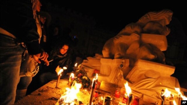 People pray near a statue in honor of quake victims during a candle rally in L'Aquila on 06 Apr, 2010, to commemorate the first anniversary of the major earthquake which struck the area