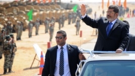 In this image released by the Egyptian Presidency, Egyptian President Mohammed Morsi, waves toward soldiers at a military base in Ismailia, Egypt, Oct. 10, 2012.