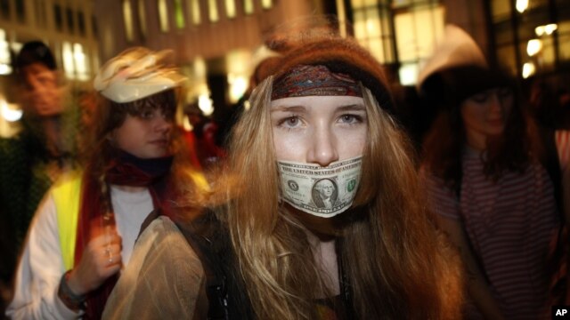 A woman dances with a US dollar covering her mouth during a protest against government austerity measures in central London November 30, 2011.