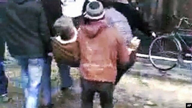 This image made from amateur video and released December 27, 2011, purports to show men carrying an injured man in Homs, Syria, December 26, 2011.