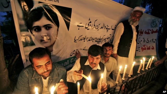 Pakistanis light candles in front of a banner showing a picture of 14-year-olschoolgirl Malala Yousufzai in Peshawar, Pakistan, Oct. 15, 2012. 