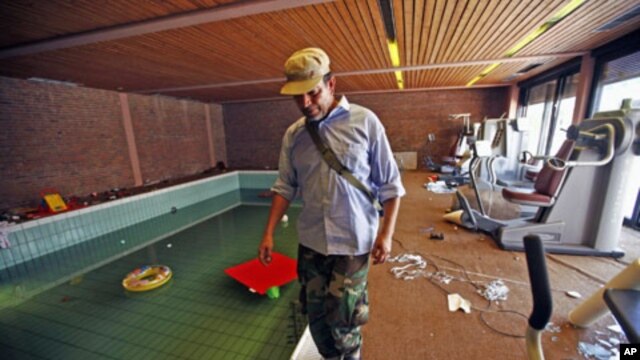 An anti-Gaddafi fighter walks next to a swimming pool in a house belonging to Moammar Gadhafi's son Hannibal, in Tripoli, August 30, 2011