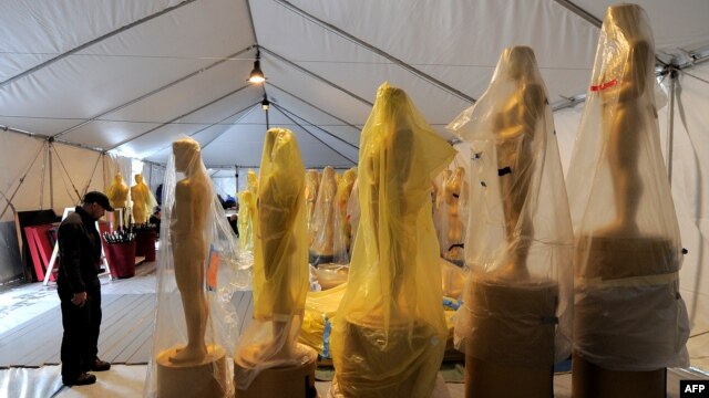 A worker stands next to the Oscar statues during a preparation work for the upcoming OSCARS, the 85th Academy Awards, at Hollywood Boulevard in Hollywood, California, February 19, 2013.