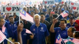 Malaysia's Prime Minister Najib Razak (C) waves a national flag as he sings patriotic songs with supporters during an election campaign rally in Rawang, outside Kuala Lumpur April 28, 2013.