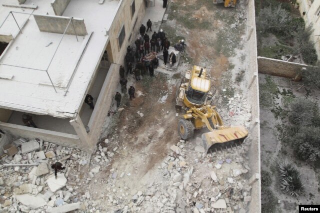 FILE - Civil defense workers remove dead bodies from under debris after an airstrike on Kafr Hamra village in the northern Aleppo countryside of Syria, Feb. 27, 2016.