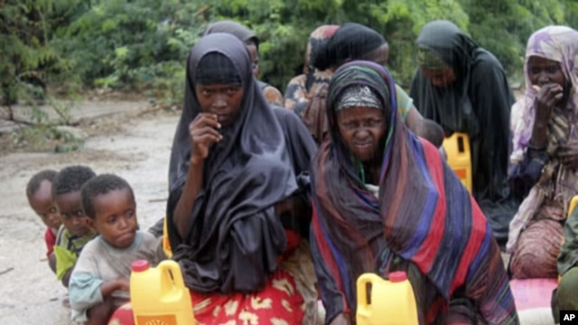 Somali women and children from southern Somalia wait in the rain with some basic rations at a displaced camp in Mogadishu, Somalia, July 15, 2011