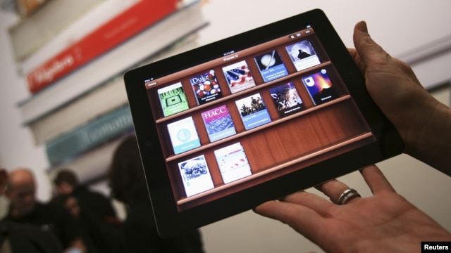 A woman holds up an iPad with the iTunes U app after a news conference introducing a digital textbook service, in New York, January 2012. (file photo)