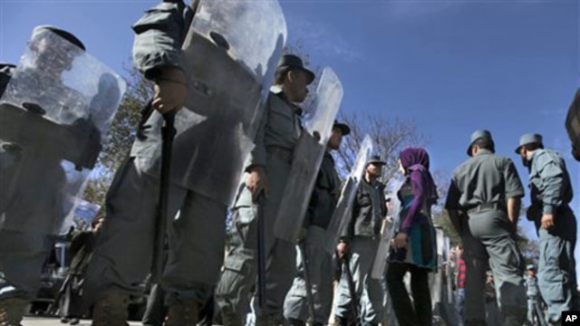 An Afghan woman protester walks past as policemen stand guard during a protest against September's parliamentary poll in Kabul, Afghanistan, 02 Nov. 2010.