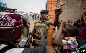 A policeman argues with a supporter of opposition leader Kizza Besigye at the gates of his party headquarters, before police who had surrounded it raided the building, in Kampala, Uganda, Feb. 19, 2016.