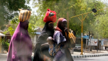 Women attempt to cross Jos Road with their belongings, after the military declared a 24-hour curfew over large parts of Maiduguri in Borno State May 19, 2013.