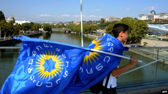 An opposition supporter carries flags of Georgian Dream coalition while celebrating victory in parliamentary polls in central Tbilisi, October 2, 2012.