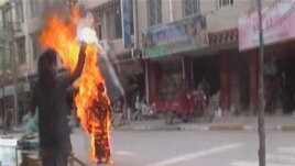 A woman throws a white scarf over Tibetan Buddhist nun Palden Choetso as she burns on the street in Daofu, China - or Tawu in Tibetan - November 3, 2011.
