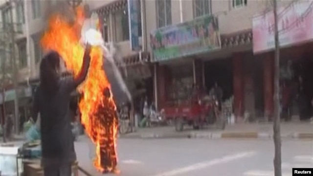 A woman throws a white scarf over Tibetan Buddhist nun Palden Choetso as she burns on the street in Daofu, China - or Tawu in Tibetan - November 3, 2011.