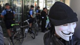 Un manifestante con una máscara de Guy Fawkes frente a miembros de la policía de Chicago, durante una de las protestas contra la reunión de la OTAN.