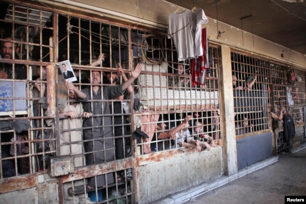 FILE - Inmates are seen behind bars in Aleppo's main prison, May 22, 2014.