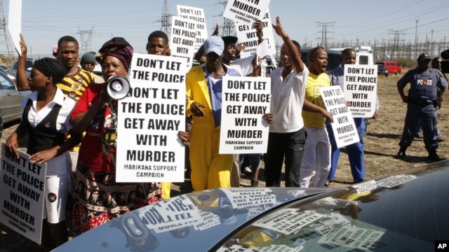 A group of protestors holds placards as a large crowd follows retired judge Ian Farlam and his team as they inspect the area where the bodies of mine workers were found after the shootings at Lonmin's platinum mine in Marikana near Rustenburg, South Africa, October 1, 2012.  