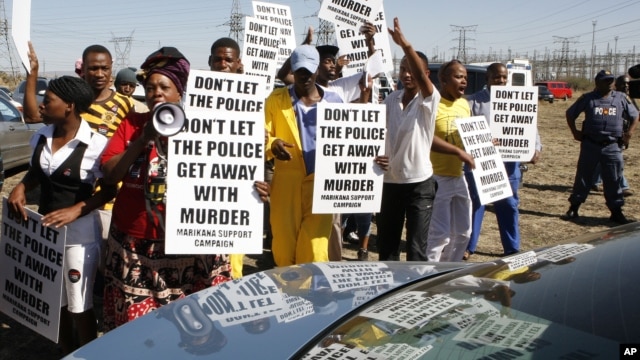 A group of protesters follow retired judge Ian Farlam and his team as they inspect the area where the bodies of mine workers were found after the shootings at Lonmin's platinum mine in Marikana near Rustenburg, South Africa,  Oct. 1, 2012.  