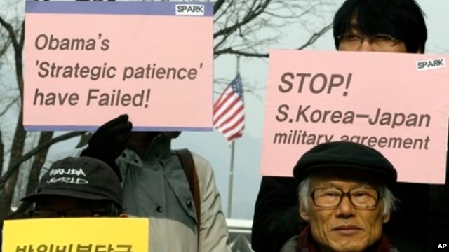 Protesters hold placards during denouncing military alliance between South Korea, the United States and Japan, Seoul, Jan. 15, 2013.