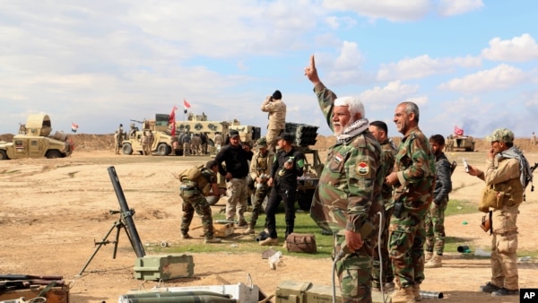 Iraqi army soldiers and volunteers prepare to launch mortar shells and rockets against Islamic State militant positions outside Tikrit, March 4, 2015.