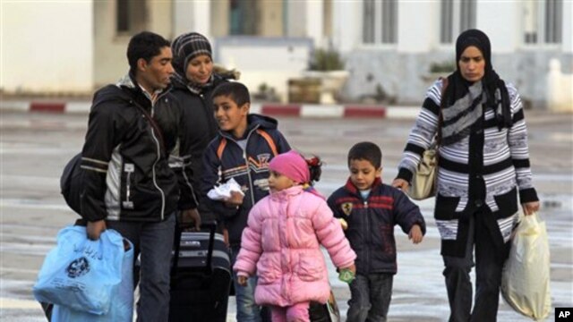 Members of a Tunisian family carry their belongings after they fled from Libya, at the Tunisia-Libya border near the village of Ras Ajdir, Tunisia, Wednesday, Feb. 23, 2011