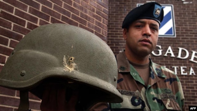 American soldier Jose Adorno holds a Kevlar helmet he was wearing when struck by a grenade explosion in Iraq several years ago