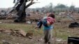 A woman carries her child through a field near the collapsed Plaza Towers Elementary School in Moore, Oklahoma, May 20, 2013.