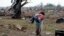 A woman carries her child through a field near the collapsed Plaza Towers Elementary School in Moore, Oklahoma, May 20, 2013.