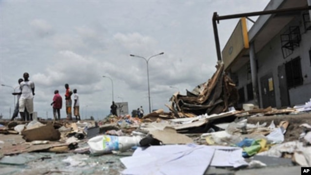 Resident walk past shops looted and destroyed in the Abobo district of Abidjan, March 2, 2011