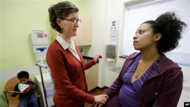 Certified nurse midwife Danielle Kraessig meets with patient Yakini Branch at a family health center in Illinois. (Jan. 2013)