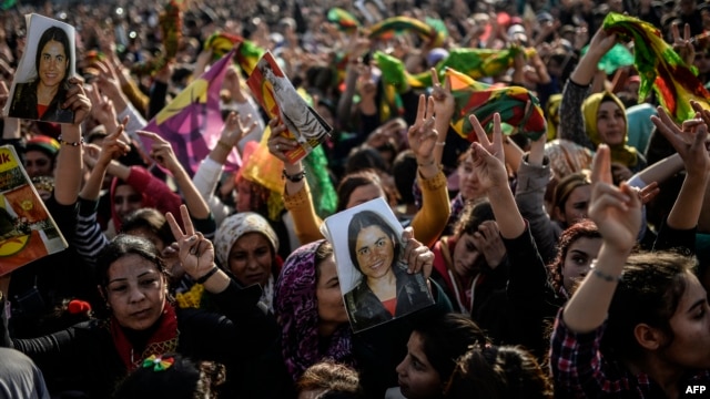 FILE - Kurds celebrating success by Kurd and peshmerga fighters to drive Islamic State militants out of Kobani hold a photo of a fighter killed in the conflict, near the Turkish-Syrian border at Suruc, in Sanliurfa province, Jan. 27, 2015.