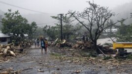 People walk through debris in Samoa's capital Apia, December 14, 2012, after cyclone Evan ripped through the South Pacific island nation. 