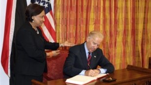 Vice President Biden, signs the guest book as Trinidad &amp; Tobago's Prime Minister Kamla Persad-Bissessar looks on in St. Anns, Trinidad. May 28, 2013. (AP Photo)
