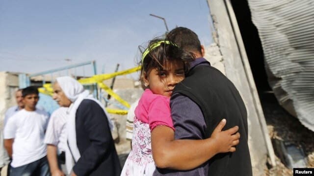 A man carrying a girl walks past by the damaged house where five Turkish civilians were killed by a mortar bomb in the southern border town of Akcakale, October 4, 2012.