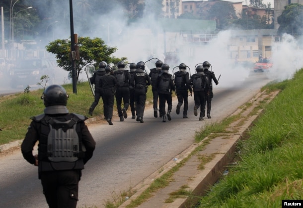 FILE - Ivory Coast riot policemen disperse opposition supporters with tear gas during a march to protest against Ivory Coast's President Alassane Ouattara's new constitution in Abidjan, Ivory Coast, Oct. 20, 2016.