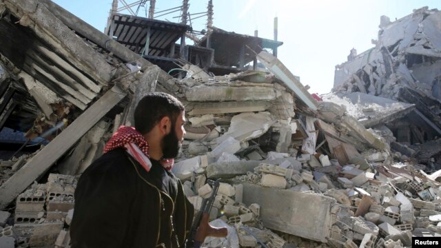 A Free Syrian Army fighter carries his weapon as he walks past damaged buildings in the Arabeen neighborhood of Damascus, Syria, Feb. 12, 2013.