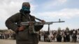 FILE - A member of the Taliban insurgents and other people stand at the site during the execution of three men in Ghazni province, Afghanistan, April 18, 2015.  