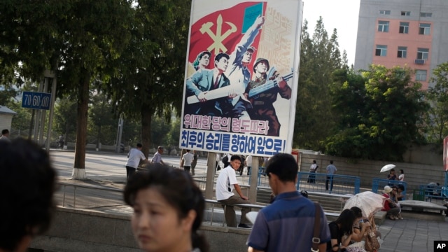 FILE - A man sits under a propaganda banner in Pyongyang, North Korea, Aug. 23, 2015.  
