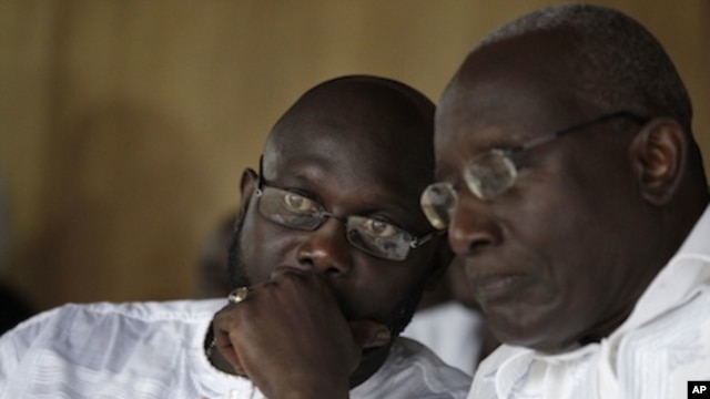 Liberian opposition presidential candidate Winston Tubman, right, talks with running mate George Weah at a rally urging their party's supporters to boycott next week's presidential polls, in Monrovia, Liberia Saturday, Nov. 5, 2011.