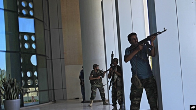 Rebel fighters take shelter as an intense gunbattle erupted outside the Corinthia hotel, where many foreign journalists are staying, in Tripoli, Libya, August 25, 2011