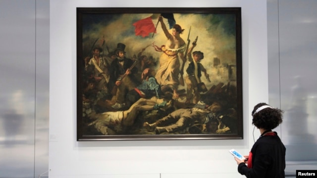 A woman looks at Eugene Delacroix 's painting, "Liberty Leading the People" (28 July 1830) during media day on the eve of the inauguration of the Le Louvre Lens Museum, December 3, 2012.  