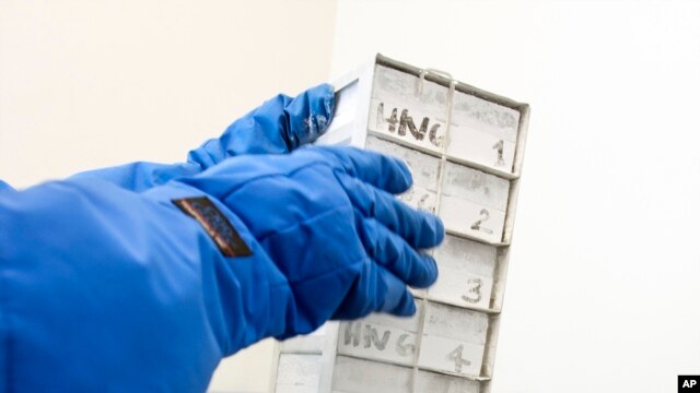 Seorang petugas tengah membuka sebuah kotak berisi sel-sel darah yang sudah dibersihkan dari protein dari dalam lemari pendingin, untuk diuji coba di 